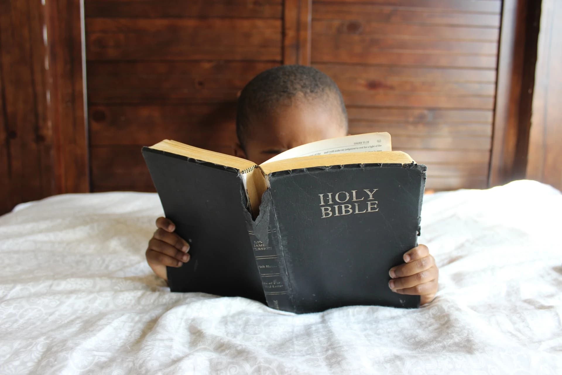 A young child holding an open Bible
